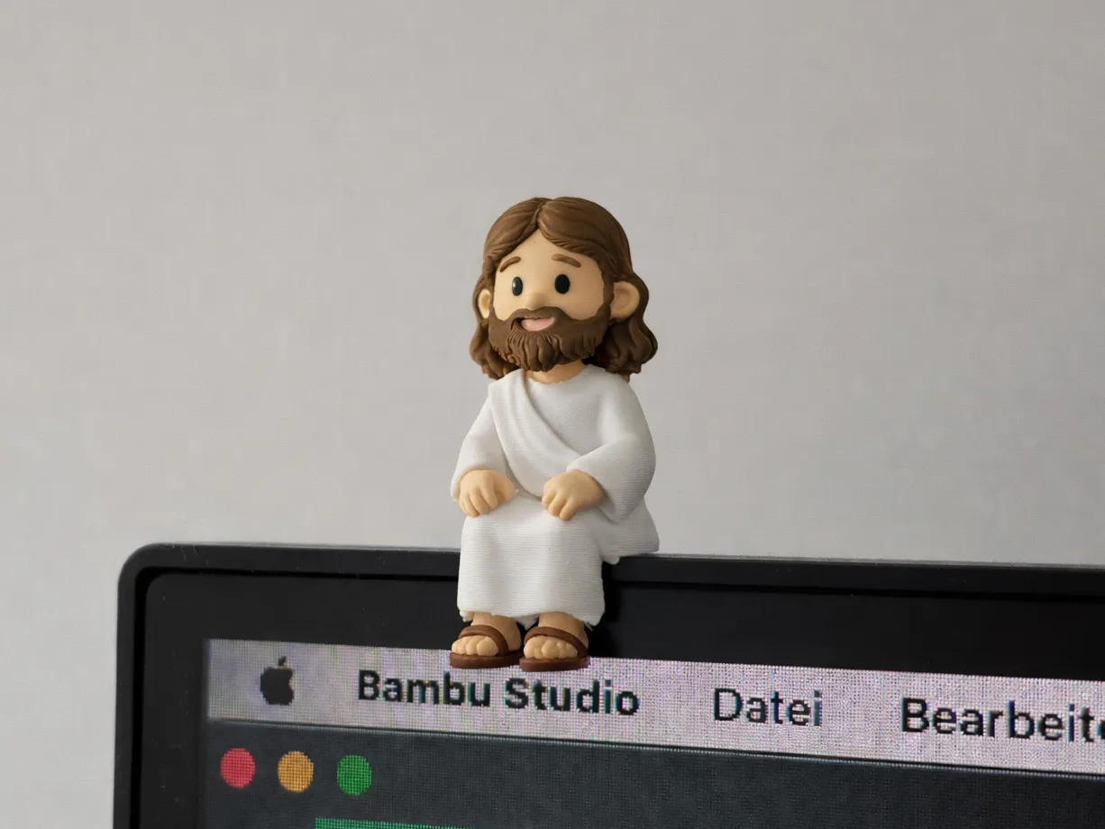 Mini Jesus sentado — arquivo digital 3MF impresso e apoiado na borda de um monitor